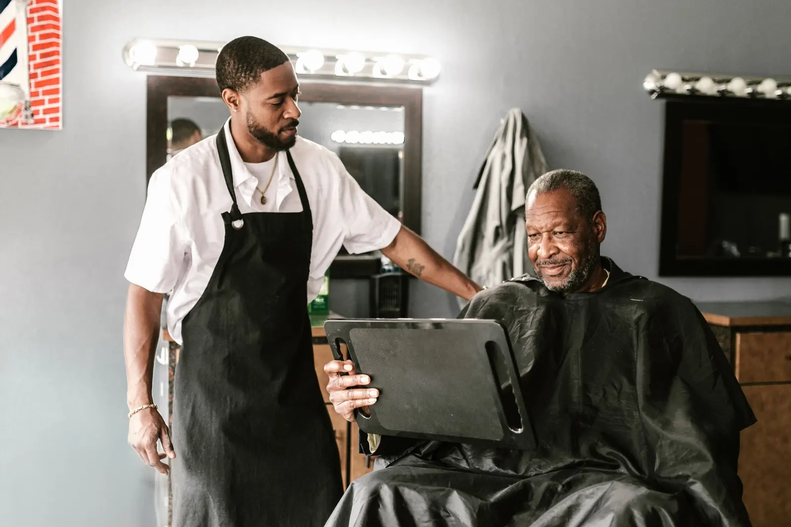 A barber shows his client the screen at the end of a visit